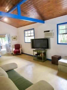 un soggiorno con divano e TV a schermo piatto di Chalé com 2 quartos na Beira do Lago Pet Friendly a Posse