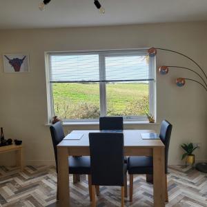 a dining room table with chairs and a window at RAWSON COTTAGE LOVELY 2 BEDROOM SEMI RURAL in Stranraer