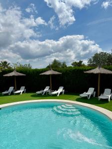 a swimming pool with chairs and umbrellas at Mirador De La Vega De Cazalla in Cazalla de la Sierra