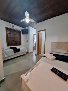 a bedroom with two beds and a ceiling fan at Suítes Pitangueiras - POUSADA FRENTE MAR in Guarujá