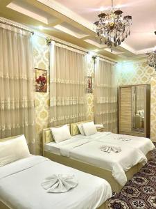 a bedroom with two beds and a chandelier at Elite Hotel in Tashkent