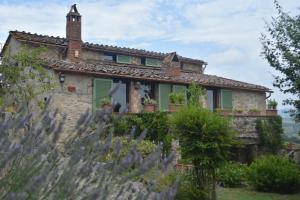 una antigua casa de piedra con persianas verdes en Celle di lecchi nel Chianti, en San Sano