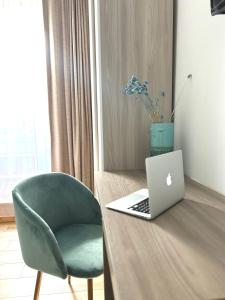 a desk with a laptop and a green chair at Le Tre Orchidee Florence in Florence