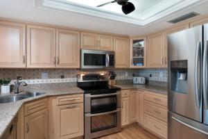 a kitchen with wooden cabinets and stainless steel appliances at Sunrise beach views with top complex amenities and pool access! in Ormond Beach