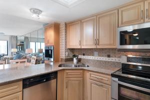 a kitchen with a sink and a microwave at Sunrise beach views with top complex amenities and pool access! in Ormond Beach