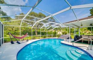 uma piscina com duas redes de descanso e um grande tecto de vidro em Spacious Citrus Hills Home with Pool and Game Room! em Hernando