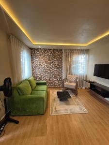 sala de estar con sofá verde y TV en Mindyourbusiness villa, en Abuja