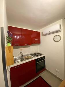 a small kitchen with red cabinets and a sink at Appartamento Rosso Marsala in Marsala +13 photos