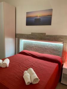 a bedroom with a red bed with two towels at Appartamento Rosso Marsala in Marsala