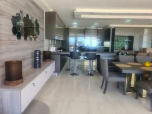 a kitchen with a bar with chairs and tables at Zimbali 20 Phezulu Villa in Ballito