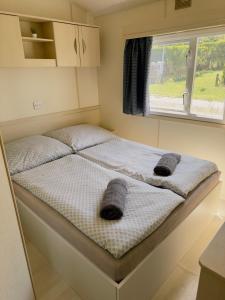 Ce lit se trouve dans une petite chambre dotée d'une fenêtre. dans l'établissement Mobilheimy Camp Výrovice, à Výrovice