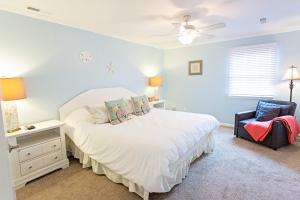 a bedroom with a white bed and a chair at Lorraine's Beach Cottage in Kure Beach