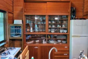 un armario de cocina con platos junto a una nevera en Forest Villa Shionine Kogen - Vacation STAY 45539v en Shiojiri