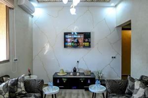 sala de estar con 2 sofás y TV en la pared en The Skyline Stay, en Marrakech
