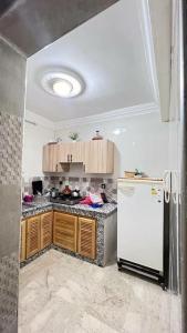 a kitchen with a white refrigerator and wooden cabinets at شقة للعائلات مفروشة in Taroudant