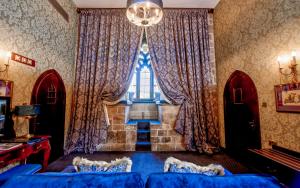 a living room with a blue couch and a large window at Langley Castle Hotel in Hexham