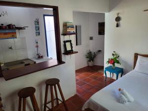 a bedroom with a bed and two stools and a mirror at Chalé Flor do Ser in Canoa Quebrada