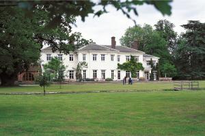 a large white house with people standing in front of it at Milton Hill House in Didcot