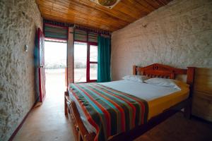 1 dormitorio con 1 cama en una habitación con ventanas en El Remanso del Santuario, en Camarones