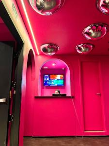 um quarto com uma parede rosa e uma televisão em Andar de Cima Suítes em São Paulo