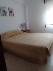 a bedroom with a large bed with a tan blanket at Apartamento sencillo Cerca del mar . in Cullera