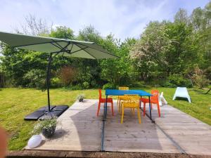 a table and chairs under a green umbrella at L'Arsouille Gîte Rural Doische in Doische