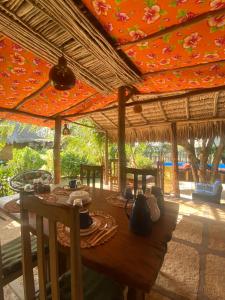 a wooden table with chairs and an umbrella at Caju Bangalôs in Ponta do Anel