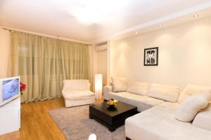 ein Wohnzimmer mit einem weißen Sofa und 2 Stühlen in der Unterkunft Slavija Square Apartments in Belgrad