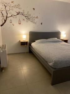 a bedroom with a bed with a tree on the wall at Au Paradis d'Ayli in Aywaille