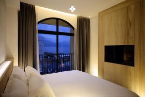 a bedroom with a bed and a window with a balcony at Chun Mure Hotel in Dahan