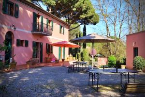 a pink house with tables and umbrellas in front of it at Villa Rosella alt in Crespina