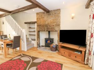 a living room with a fireplace and a flat screen tv at Katie's Cottage in Skipton