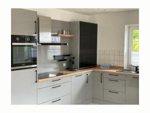 a kitchen with white cabinets and stainless steel appliances at Holiday apartment Beach Smile Lodge in Hohenfelde +13 photos