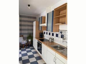 a kitchen with white cabinets and a checkered floor at Holiday apartment 2 in the Maaßen country house in Stakendorf