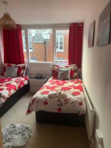 a bedroom with two beds with red curtains and a window at Jeans Place Watergate St Rows near racecourse in Chester