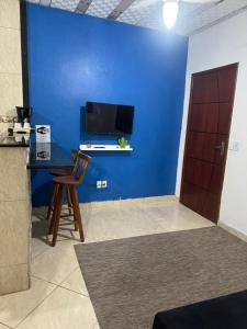 Cette chambre est dotée d'un mur bleu avec une table et une chaise. dans l'établissement hospedagemsaopedro apartamento com garagem a 13 km de Cabo frio 22 km de arraial do cabo, à São Pedro da Aldeia