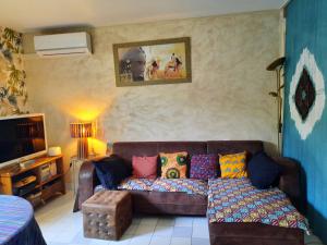 a living room with a brown couch with colorful pillows at La Villa Bleue in Beauchastel