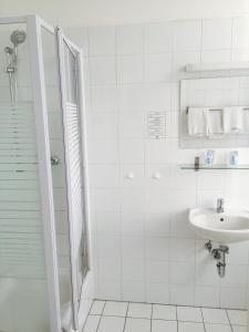 a white bathroom with a sink and a shower at Hotel Westend in Cologne