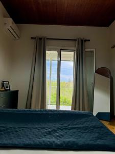 a bedroom with a bed and a large window at Captain Christos Family Garden House in Lefkimmi