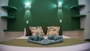 dois elefantes de peluche deitados numa cama com paredes verdes em Pousada La Luna em Paracuru