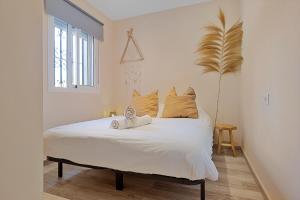 a bedroom with a bed with white sheets and a plant at Casa Pitaya in Alhaurín el Grande