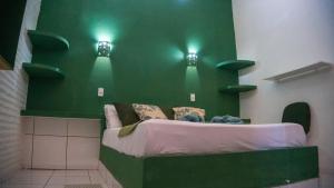 a green room with a bed with two lights on it at Pousada La Luna in Paracuru