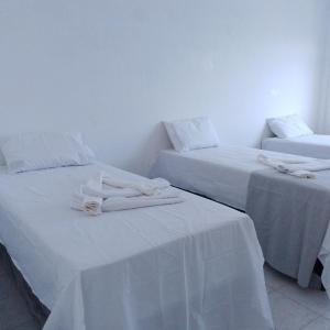two beds in a room with white sheets at Angelus Hotel & Estacionamento in Campos dos Goytacazes +18 photos