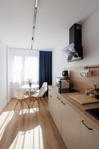 uma cozinha com armários brancos e uma mesa com cadeiras em Oboźna 25 em Zamość