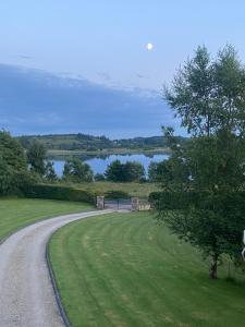 a winding road next to a field and a lake at The Ranch in Leitrim