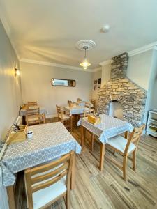 a restaurant with tables and chairs and a stone fireplace at Greenville B&B in Kenmare