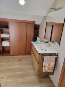 a bathroom with a sink and wooden cabinets at Ventana al Atlantico - House across from the beach in Porto do Son