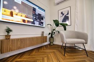 a living room with a chair and a television on a wall at Apartament Indigo 11 by Housine in Zator