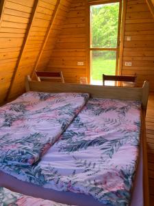 een bed in een blokhut met een raam bij Kuća za odmor KRNJAIĆ in Bosanski Novi