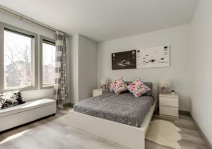 a white bedroom with a bed and two windows at Newly Renovated Vacation Home w/ Hot Tub & Garage in Calgary